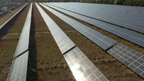 Fly-above-rows-of-solar-cells-reflecting-sunshine.-Aerial-view-of-large-renewable-energy-source.-Green-energy,-ecology-and-carbon-footprint-reduction-concept