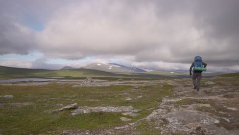 a hiker is walking towards a mountain peak in the summer