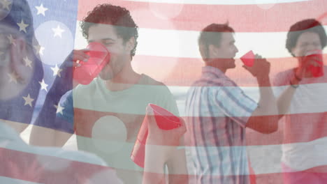 animation of flag of usa over happy diverse friends at beach party in summer