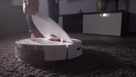 mano femenina sacando el recipiente de polvo de la aspiradora