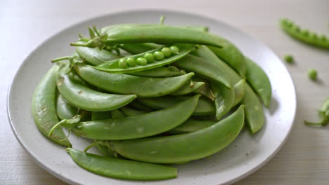 guisantes verdes dulces frescos en un plato blanco