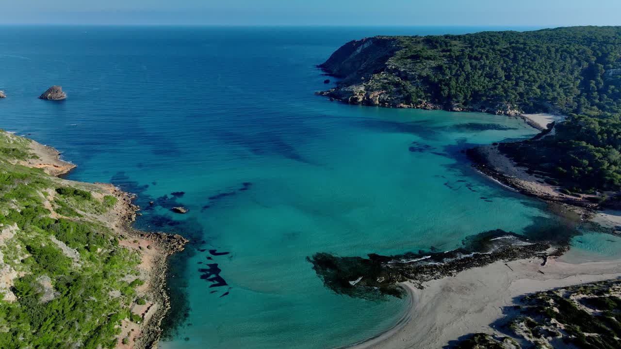 Ampia panoramica con drone della spiaggia vergine di sabbia di La Vall, Minorca, con dolci onde blu