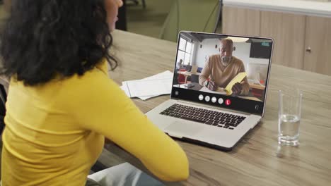 Mujer-Birracial-Usando-Una-Computadora-Portátil-Para-Videollamada,-Con-Un-Colega-De-Negocios-En-La-Pantalla