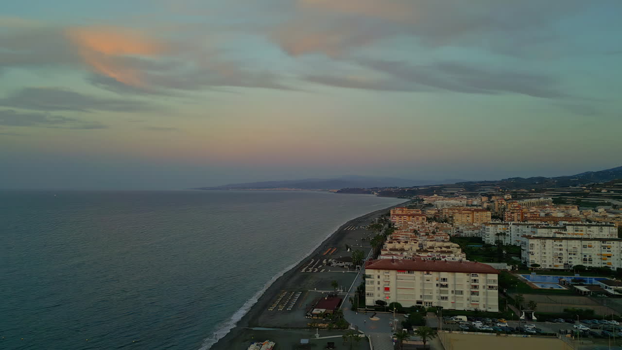 Ripresa aerea panoramica della splendida costa di Malaga, Spagna, che si affaccia sul mare con onde calme ed edifici storici della città durante l'ora d'oro