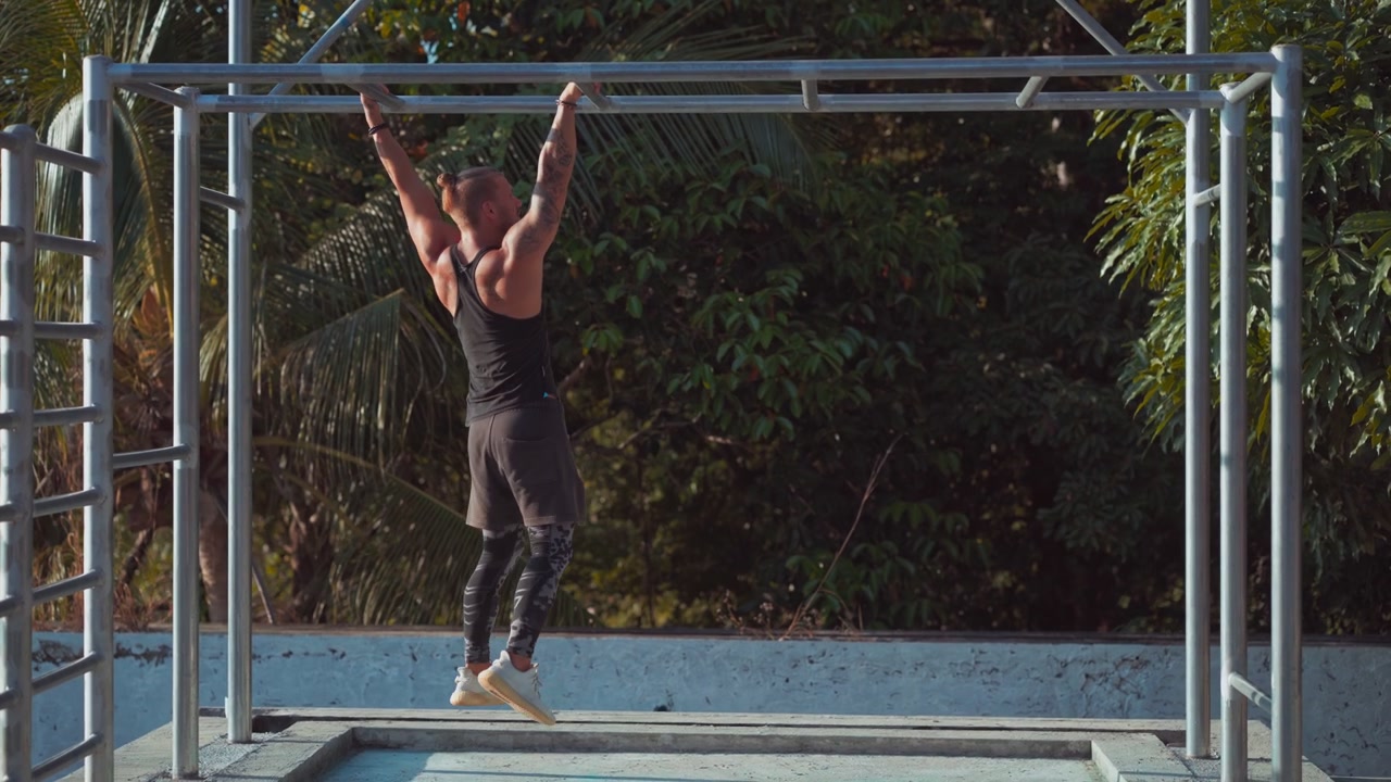 Athletic Man Performing Monkey Bar Exercises Outdoors