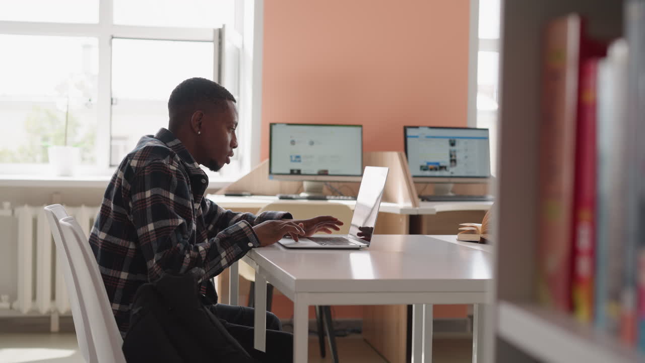 Man works with laptop in computer class. Black guy immersed in internet surfing uses college laptop equipment for seeking. Preparation with technology
