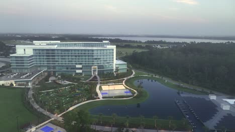 tennis fields, palm trees, solar panels on roofs and modern company building of kpmg, orlando. foggy sunset time in florida. aerial tilt up wide shot