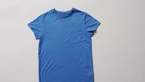 Video-Der-Flachen-Lage-Eines-Blauen-T-Shirts-Mit-Kopierraum-Auf-Weißem-Hintergrund