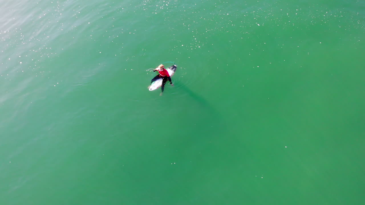 surfista solitario en el océano pacífico esperando la ola - buscando amigos, auge de drones aéreos de 4k hasta el surfista zander adelsohn en guardia de erupción de traje de neopreno rojo en la playa de huntington, competencia de surf de california