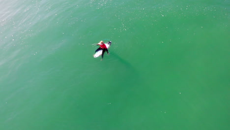 surfista solitario en el océano pacífico esperando la ola - buscando amigos, auge de drones aéreos de 4k hasta el surfista zander adelsohn en guardia de erupción de traje de neopreno rojo en la playa de huntington, competencia de surf de california