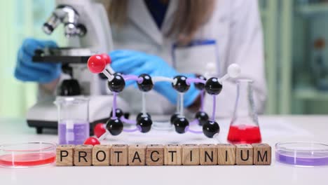 scientist in a chemistry lab with protactinium molecular model