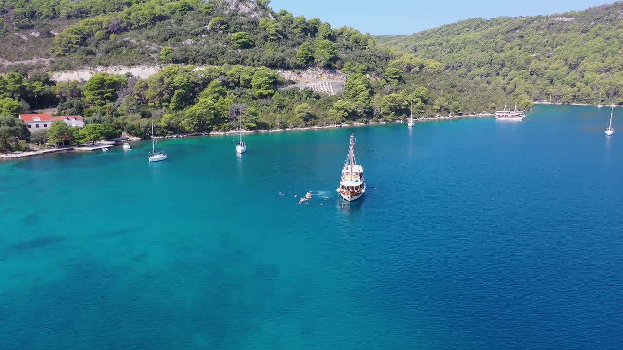 Barca turistica ormeggiata in acque tropicali, turisti che nuotano nel mare, rivelazione aerea