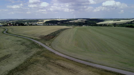 Expansive-rural-landscape-with-open-fields,-road,-and-picturesque-sky