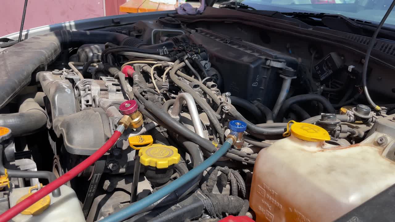 Refilling refrigerant in car with red and green tubes for air conditioning