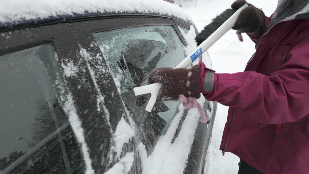 una mano raspando el hielo de la superficie del coche - cerca