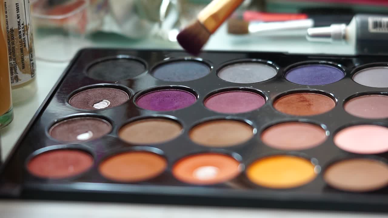 Spreading the make-up brush in purple color of the palette. Static close up