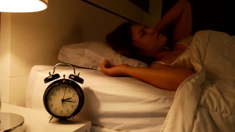 reloj con el sueño en la noche. la mujer no puede dormir