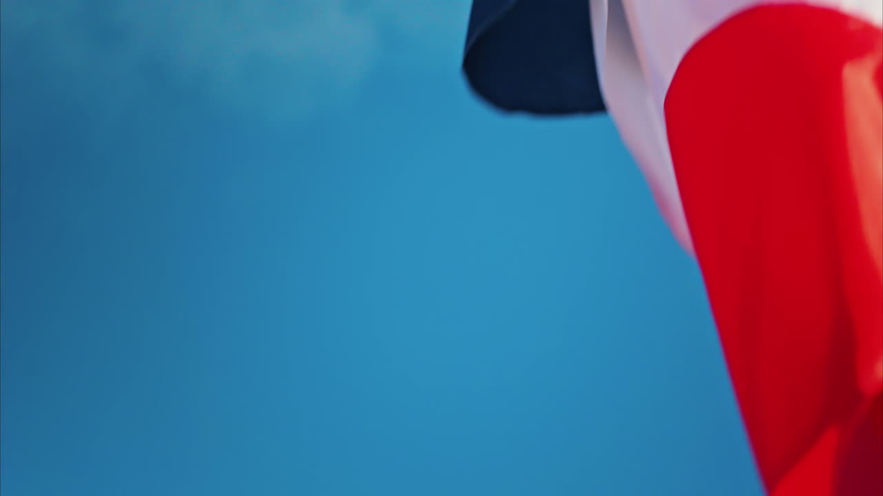 Close up of the French flag waving with the blue sky on the background