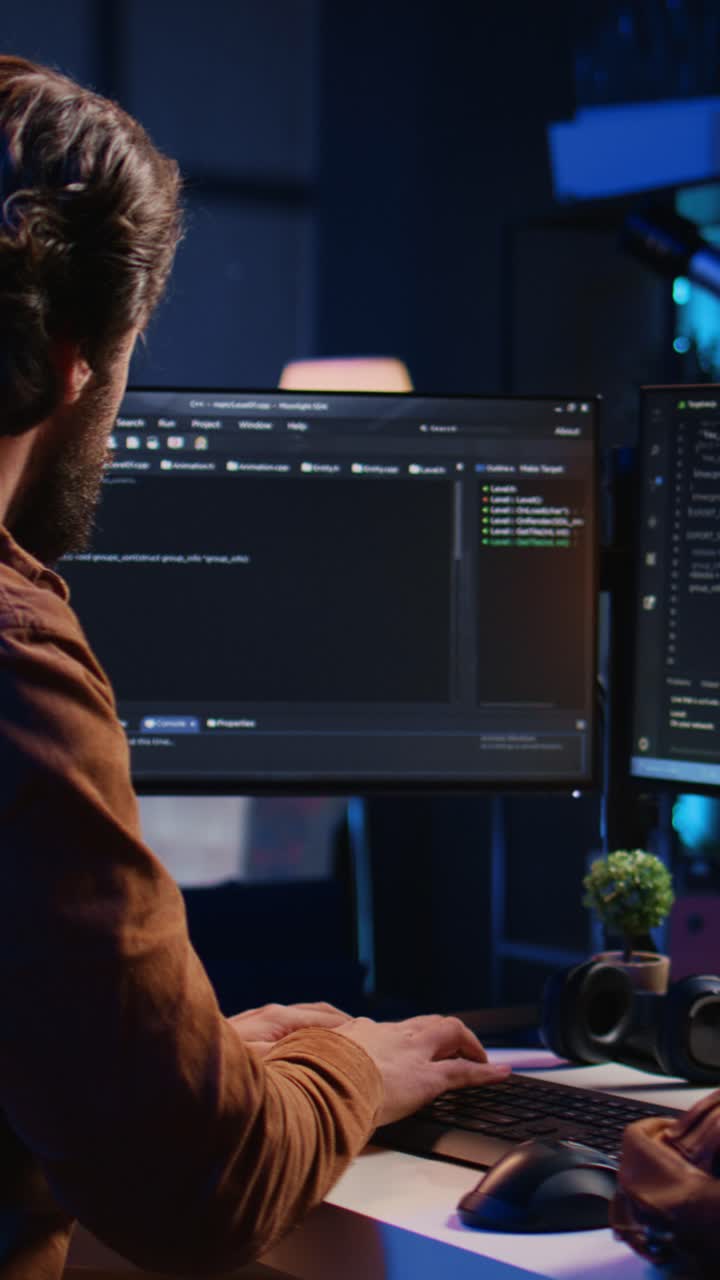 Man Programmer Coding on Multiple Computer Screens in Dark Office
