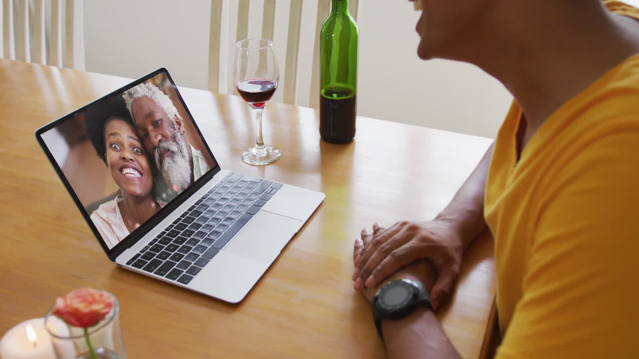 Mid section of african american man talking on video call on laptop at home