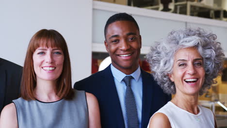 Group-of-business-partners-smiling-to-camera-in-an-office