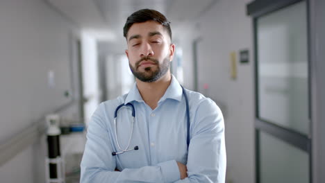 Confident-young-Asian-doctor-in-medical-attire-stands-in-a-hospital-corridor