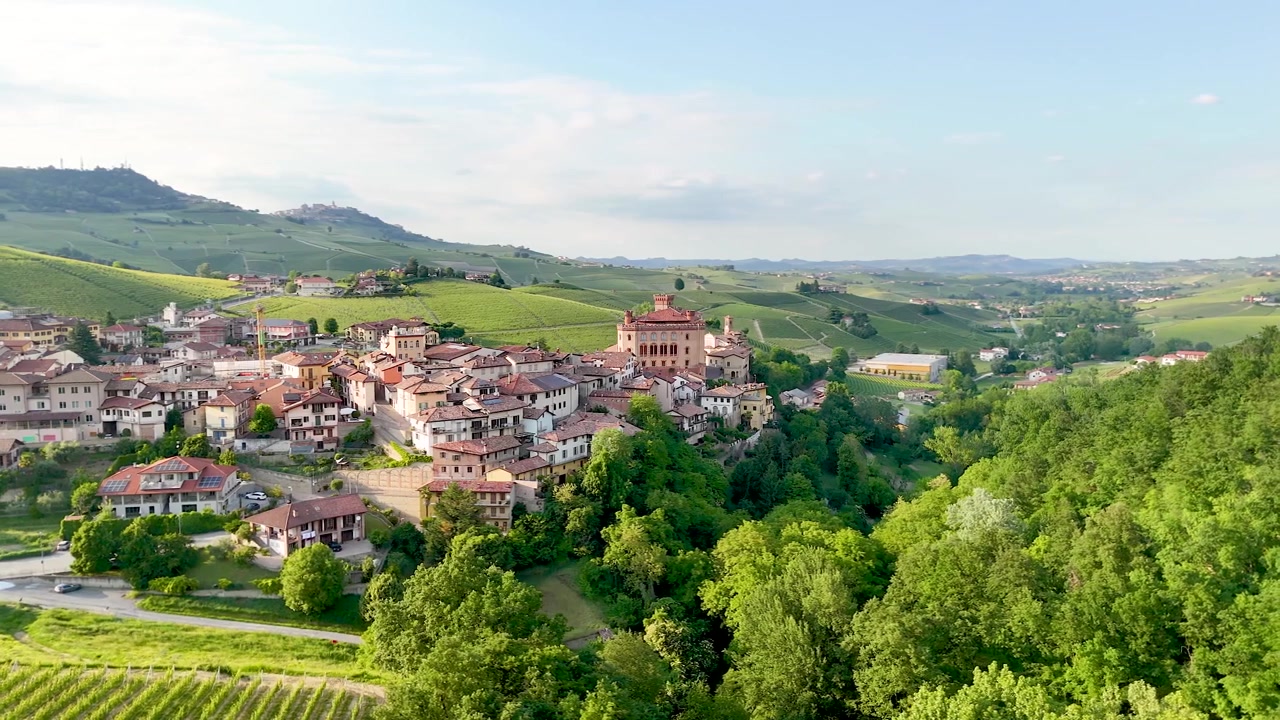 Ampia ripresa aerea con drone di un borgo storico italiano circondato da dolci colline di vigneti.