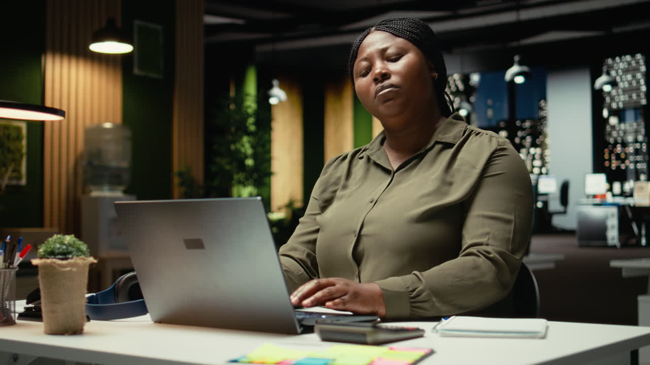 Black female entrepreneur correcting her pose and stretching her neck muscles