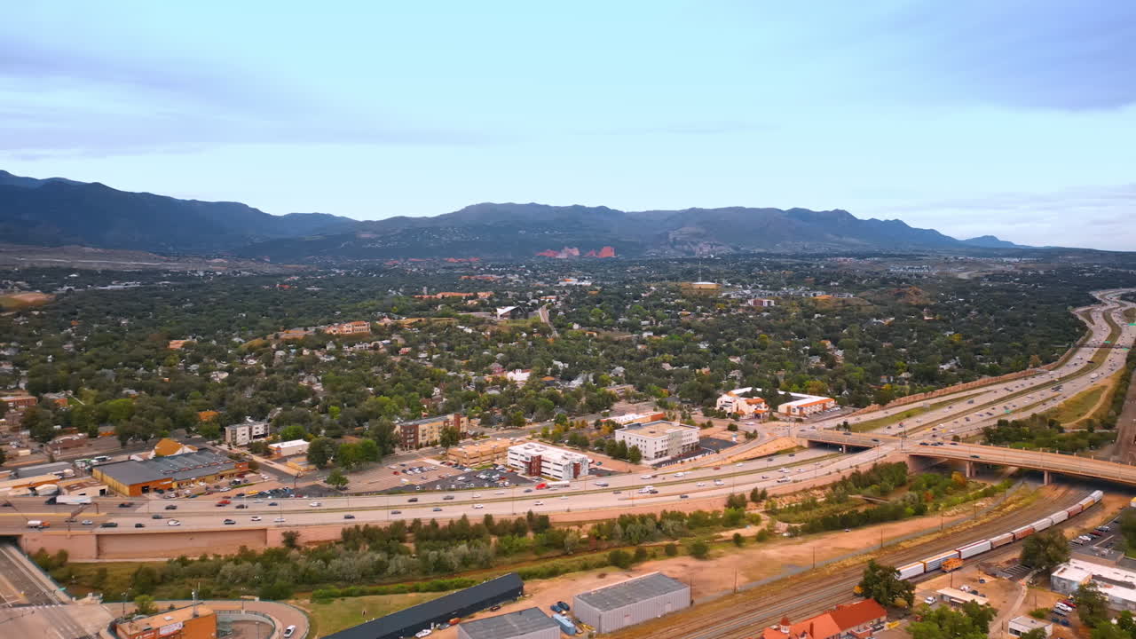 Crazy traffic on the highways of Colorado Springs, Colorado, USA. Drone footage over the green cityscape surrounded by the mountain range
