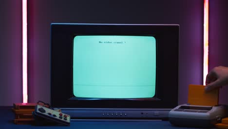 old television with blue screen on purple neon background. close-up of vintage tv and retro playstation, changing cartridges. antique video game, nostalgia