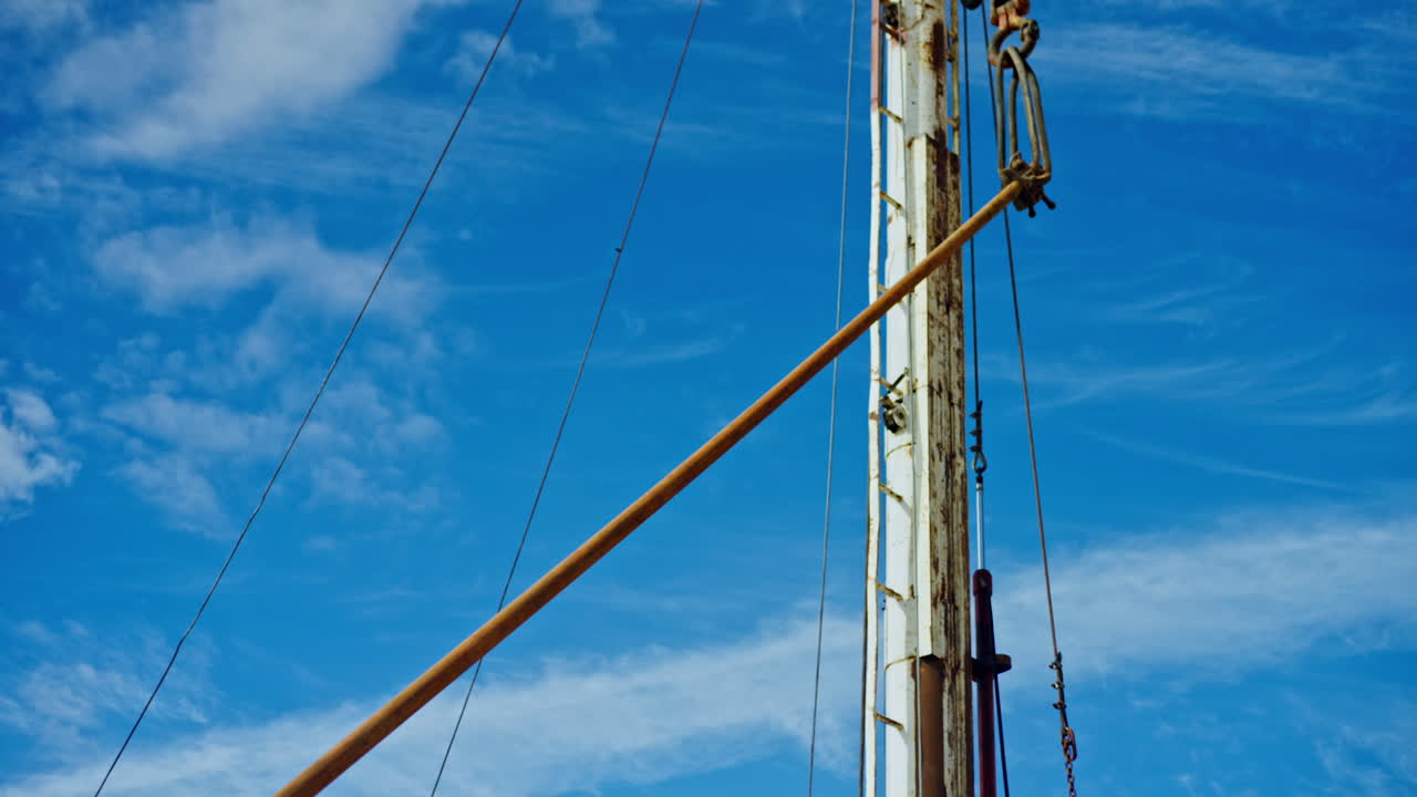 Crane hook lifts the long metal pipe. Low angle view. Arranging equipment for oil or gas production.