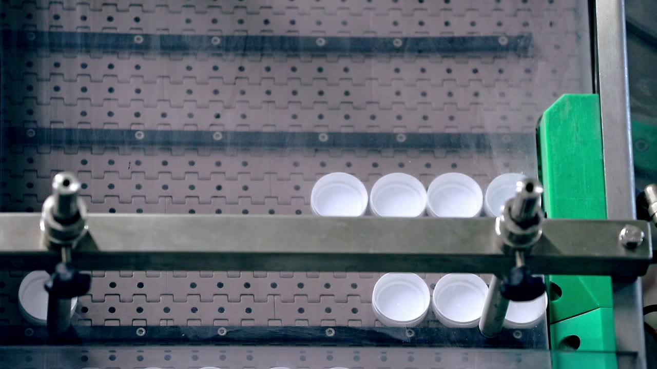 Plastic bottles caps on automated conveyor. Modern equipment for food packaging