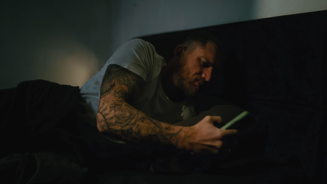 Man using phone in bed at night
