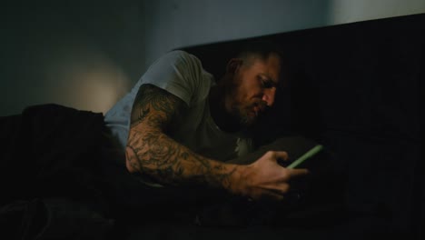 man using phone in bed at night