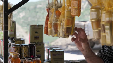 male hand pointing on local food products hanging at souvenir shop in crete, greece