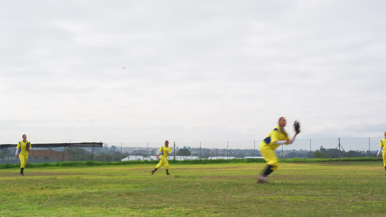 Multiracial female baseball players and male umpire, throwing the ball on a pitch, copy space