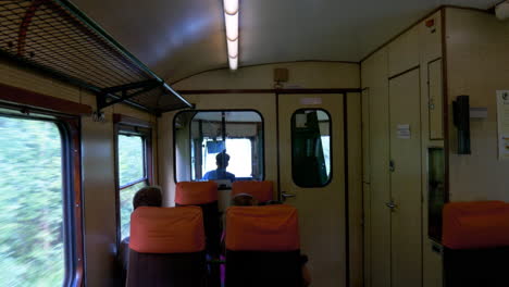 mirando a través de las ventanas delanteras de un viejo tren naranja - vagón que se mueve, con gente en primer plano