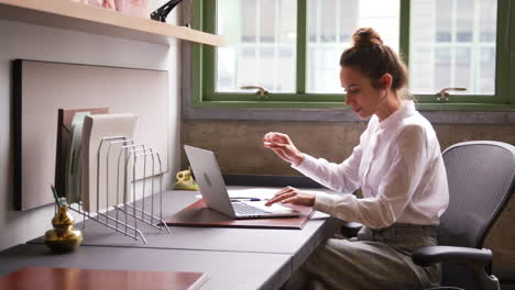 Woman-reading-document-and-using-laptop-in-office,-close-up