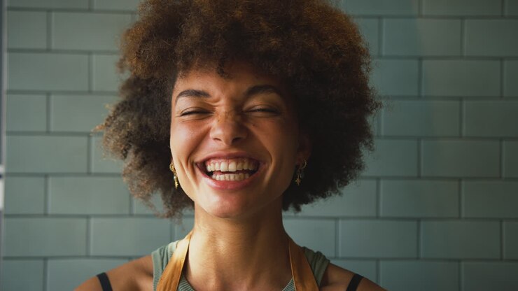 Portrait d'une propriétaire ou employée de café souriante, portant un tablier à l'intérieur d'un magasin ou d'un café.