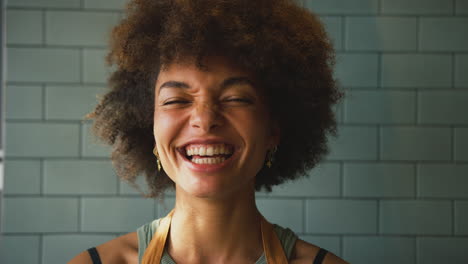 Portrait-Of-Laughing-Female-Owner-Or-Member-Of-Staff-Wearing-Apron-Inside-Shop-Or-Cafe