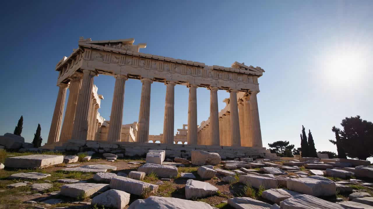 Low-angle video shot of ancient Greek temple ruins under a clear blue sky
