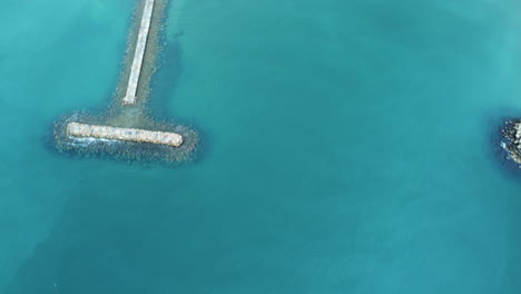 aerial view of a pier and breakwater in turquoise water