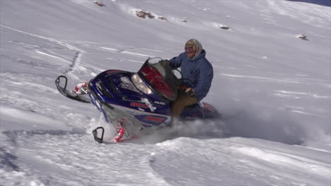 Male-snowmobiler-backcountry-powder-slow-motion-cinematic-mid-winter-fresh-snow-blue-skies-Colorado-at-Vail-Pass-early-morning