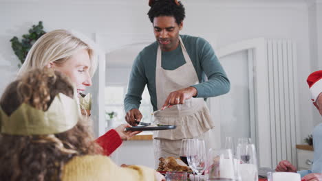 father serving food at multi-generation family christmas meal at home