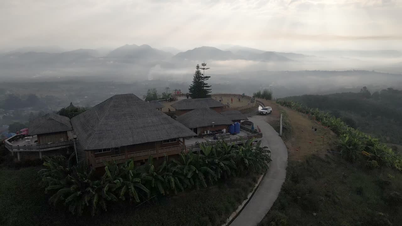 Orbit shot of the viewpoint and mountain during sunrise with fog and haze around the village