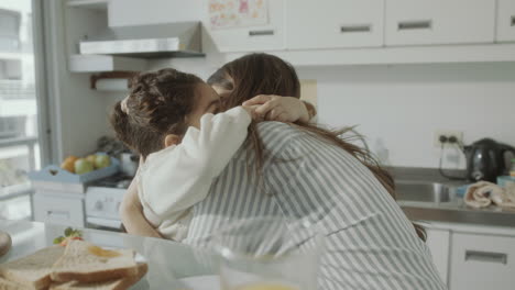 joyous girl chatting and hugging with mother on breakfast