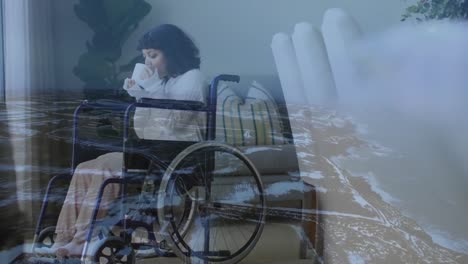 Animation-of-landscape-overlay-over-woman-in-wheelchair-drinking-tea