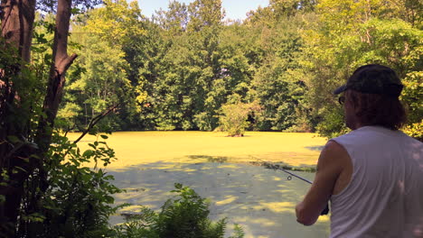 man fishing in a pond with algae