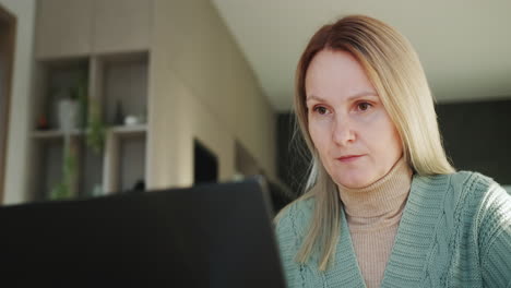 portrait of middle-aged woman works at home, uses a laptop. remote work from home