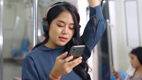 mujer joven usando teléfono móvil en un tren público